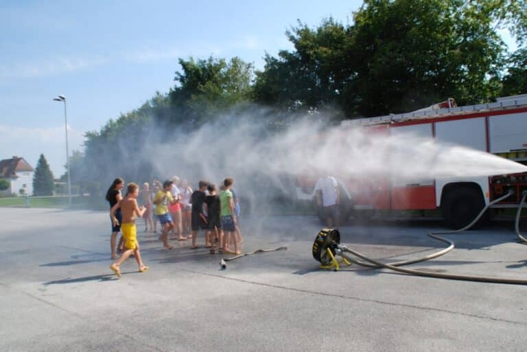 Feuerwehr sprüht Wasser über die Kinder